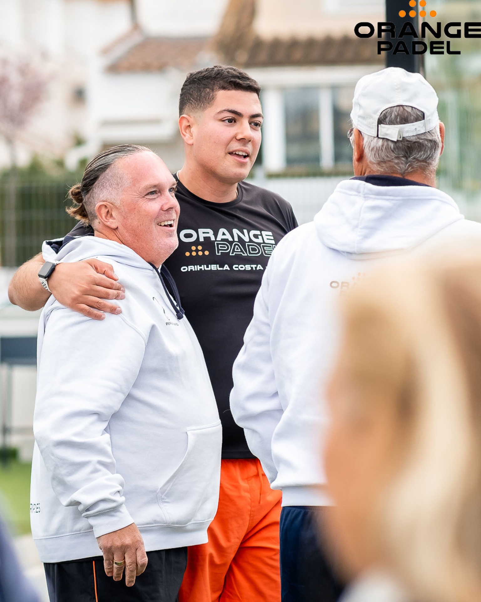Spelare i Orange Padel Orihuela Costa-tröjor umgås före match